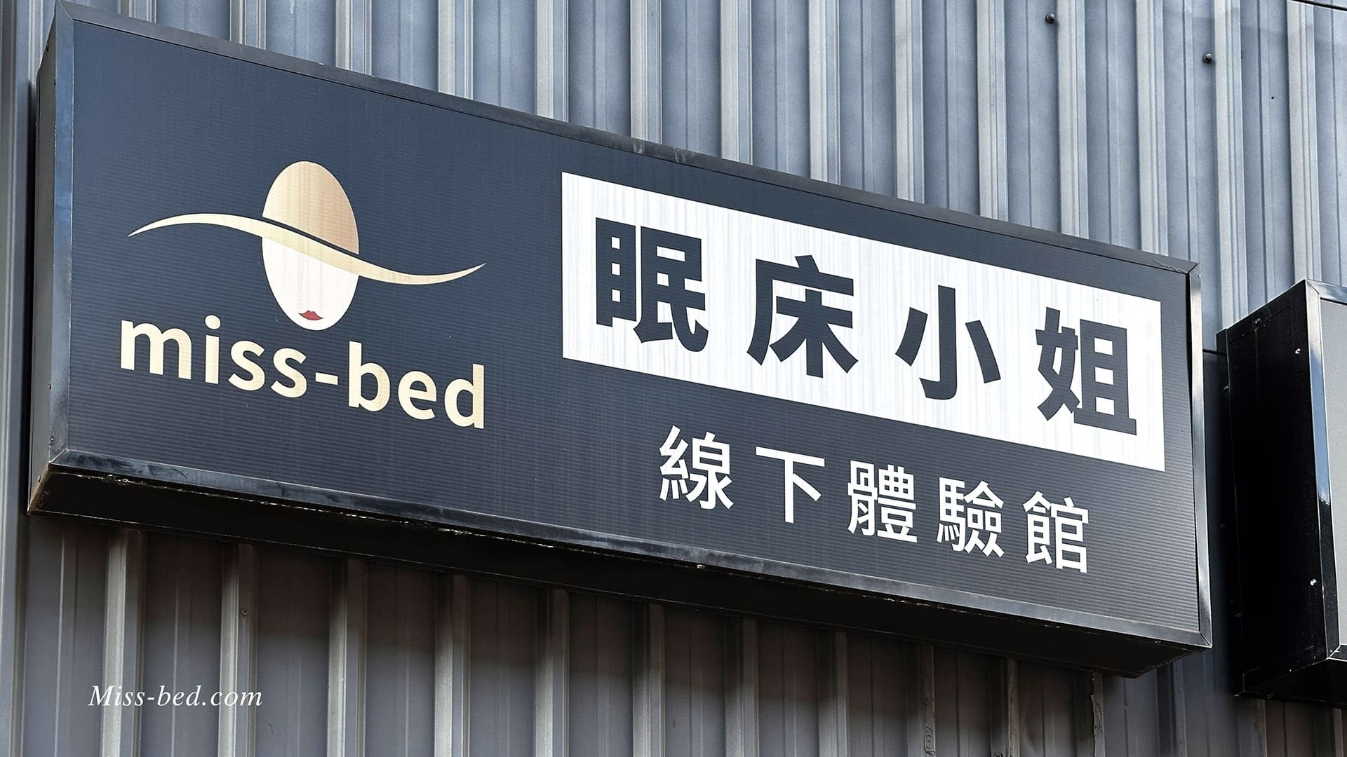 港花市旁巷子進入不久便能看到眠床小姐招牌，整體建築外觀是黑色的。