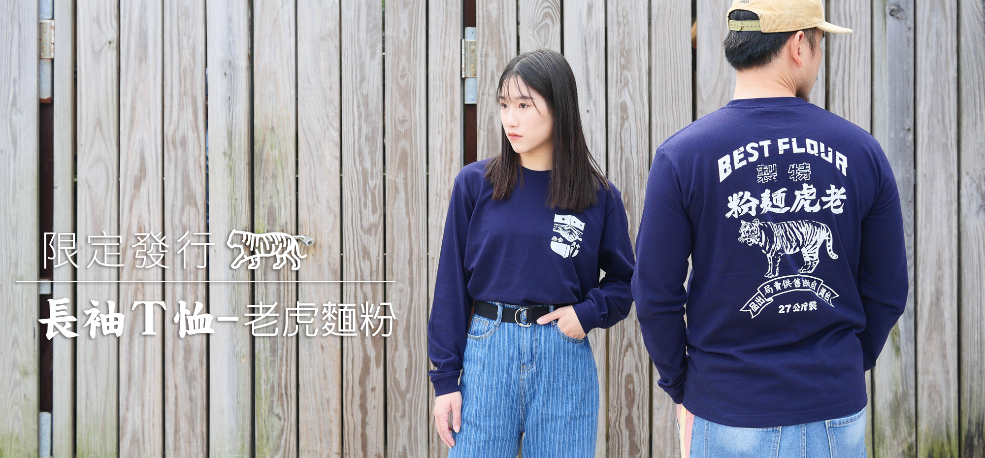 木隔柵前站著一男一女，身穿藏青色長袖T恤，一正一反，正面左胸口有畫:中美合作，背面畫老虎麵粉的圖樣。左側文字：長袖T恤-老虎麵粉，限量發行