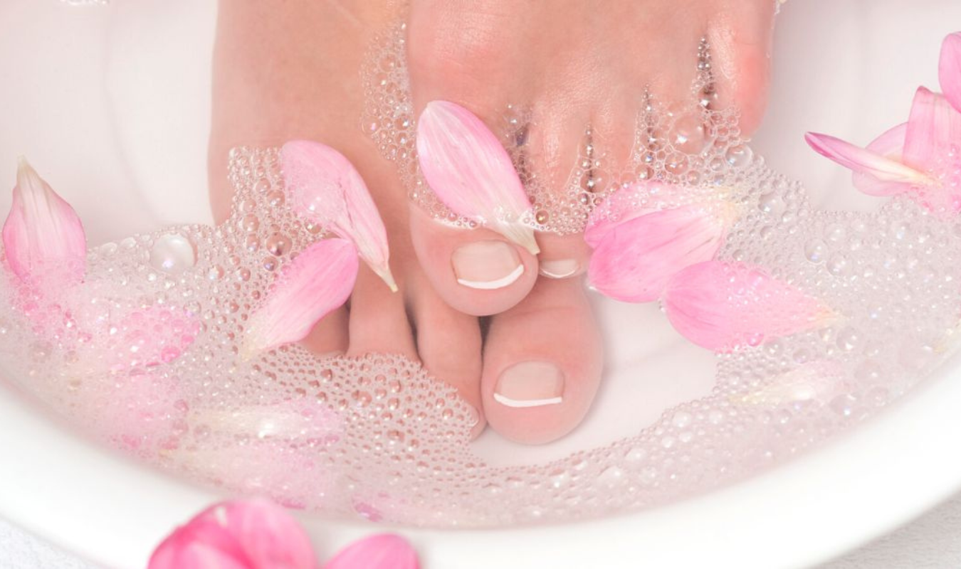 在有著粉色花瓣的熱水盆中泡腳的女人｜逗DOLLSPA耳燭