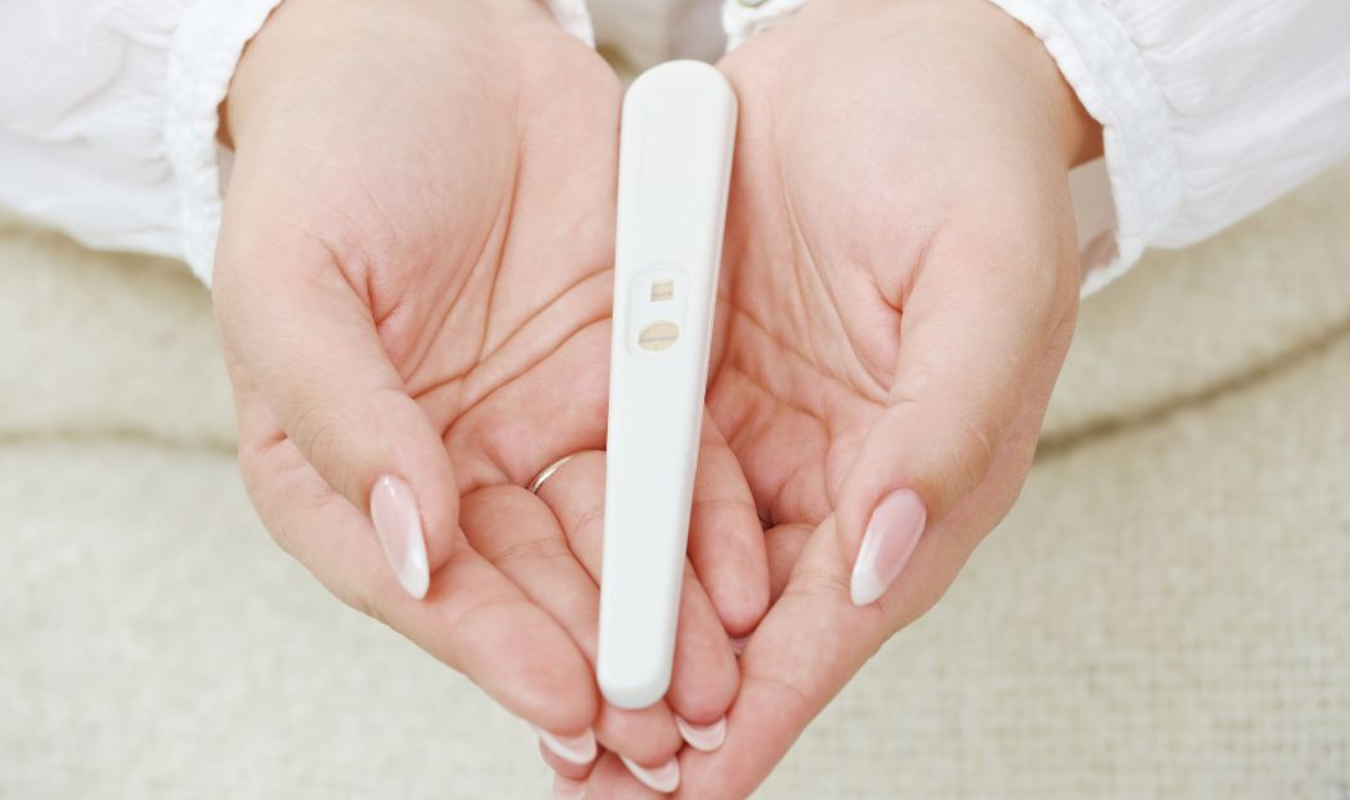 一個想懷孕的女人用雙手捧著一支驗孕棒｜逗DOLL SPA暖宮