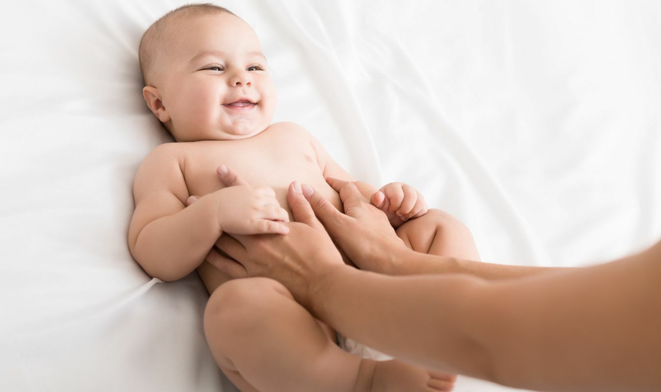 雙手放在寶寶肚臍兩側進行按摩的畫面｜逗DOLL SPA好孕寶寶純淨按摩油