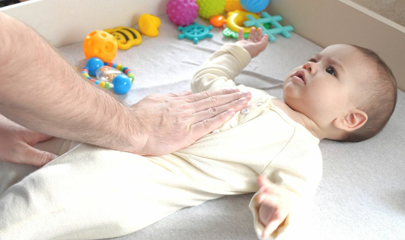 右手放在寶寶左腹上方向下滑動的畫面｜逗DOLL SPA好孕寶寶純淨按摩油