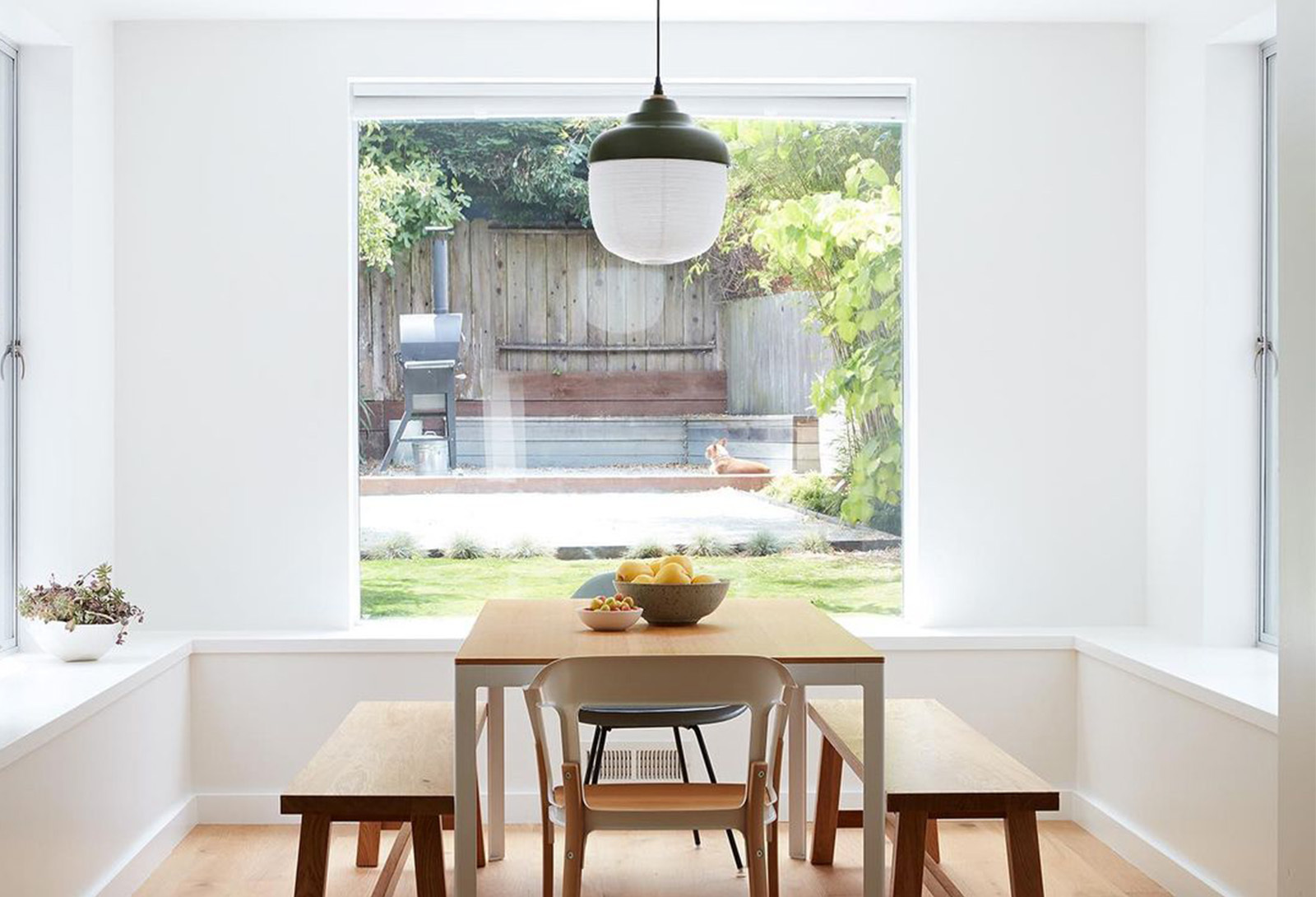 明亮自然採光的空間，餐桌上吊掛著一盞燈籠造型的餐桌燈。
