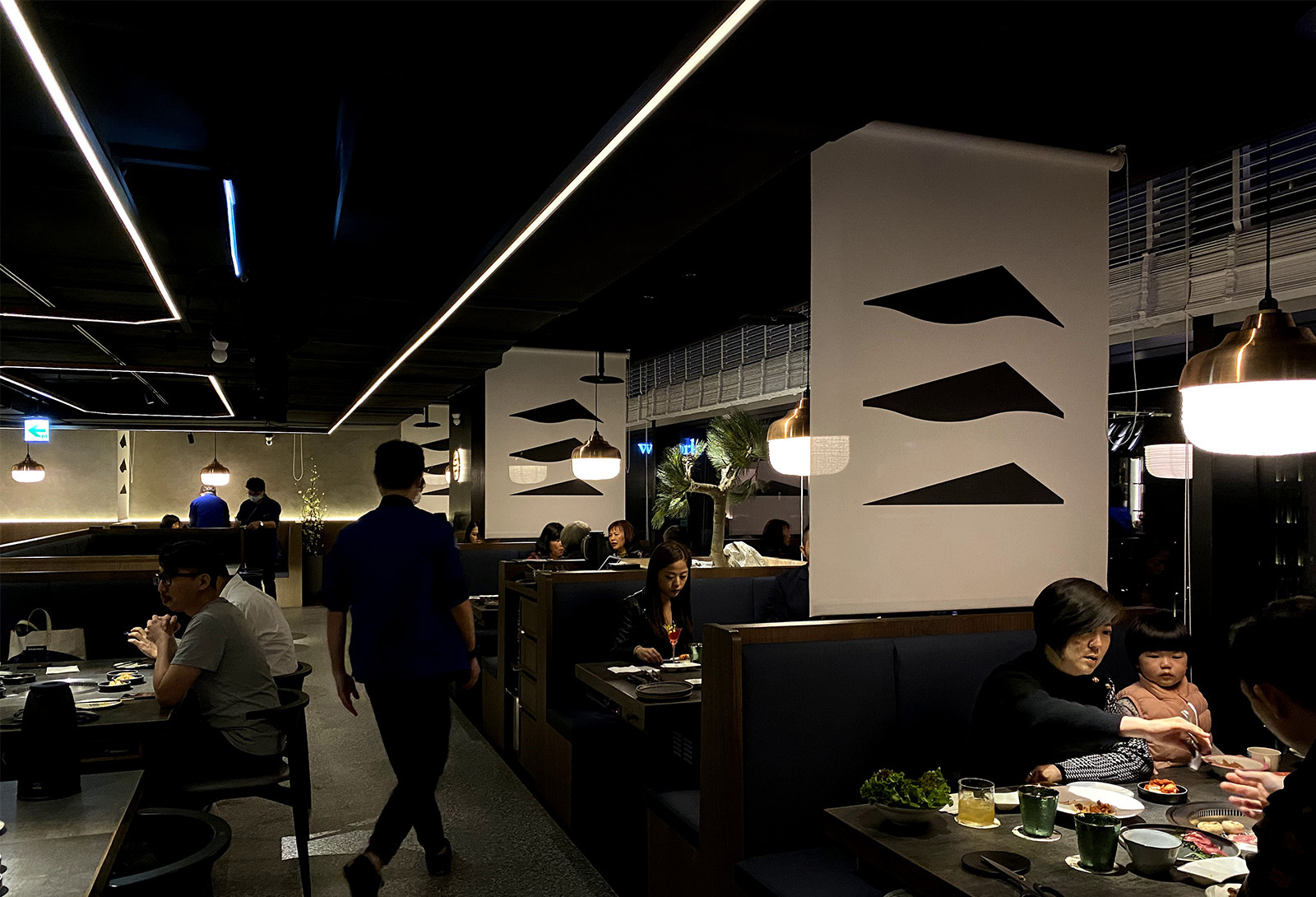 韓式燒肉店用餐區餐桌上，吊掛著數盞紅銅燈罩結合紙燈籠的吊燈