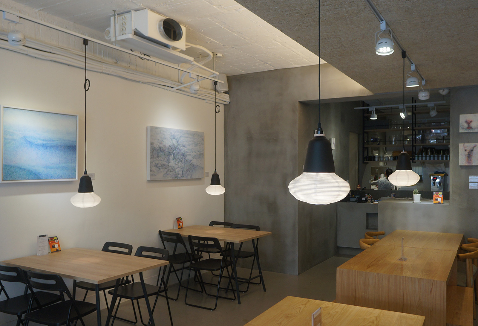 木餐桌上吊掛著金屬結合紙燈籠設計的吊燈