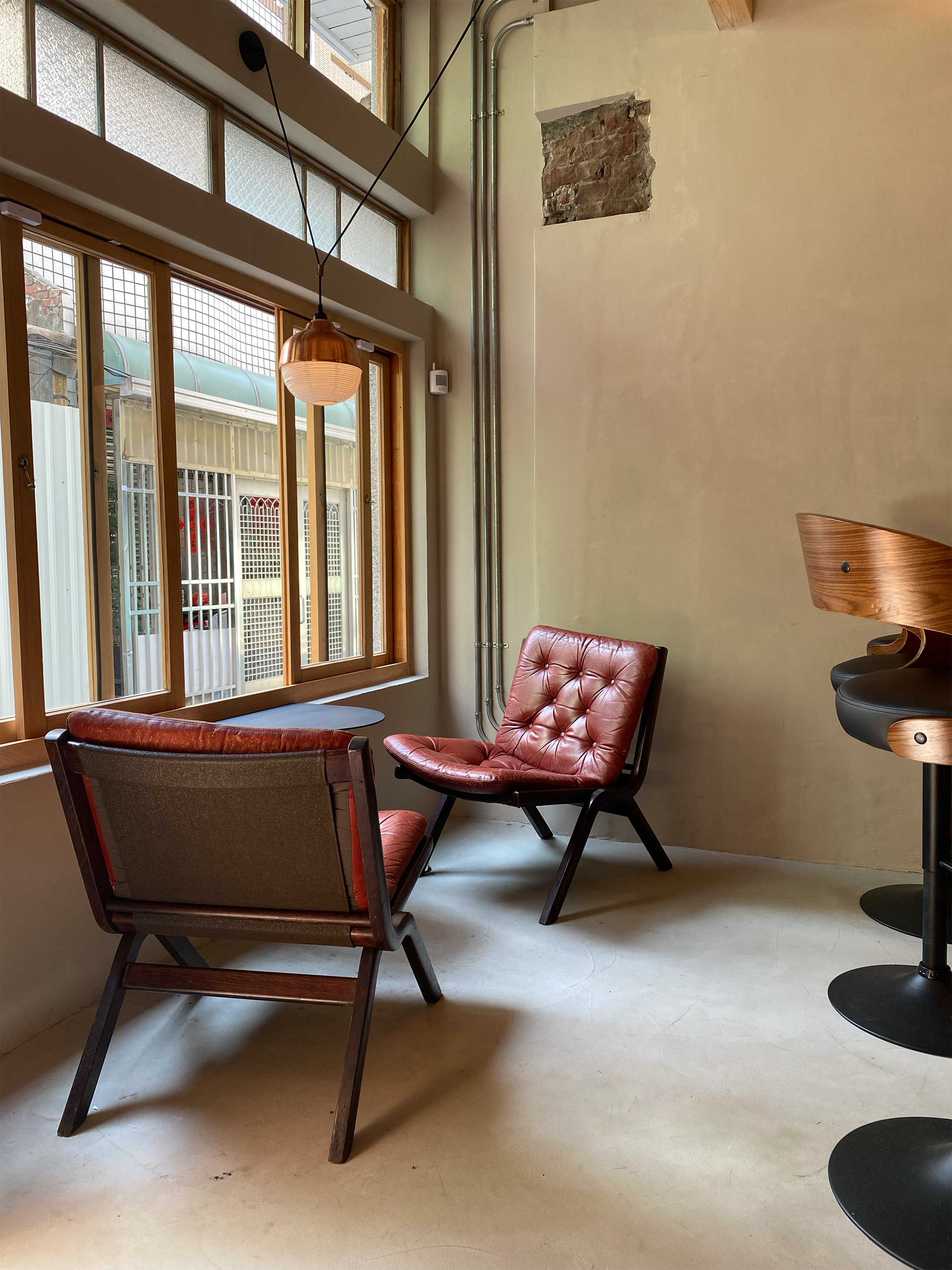 台南燕咖啡窗邊座位，兩張紅色皮革單椅搭配一盞紅銅燈罩結合燈籠設計的吊燈