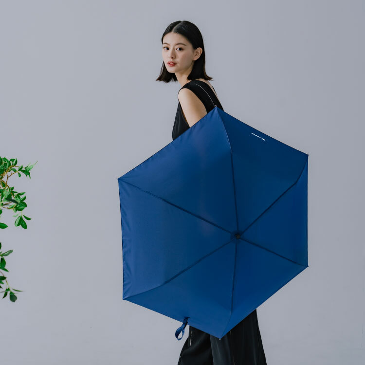 一個女人撐著一把，輕便好攜帶的深藍色雨傘