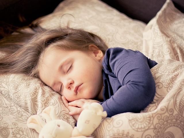 包著過夜尿布的小女孩和泰迪熊一起睡覺。
