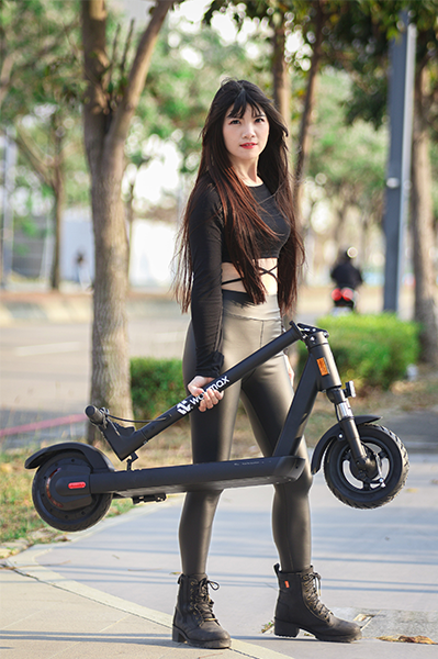 一位穿著皮長褲的女生，單手抬起Waymax R10電動滑板車