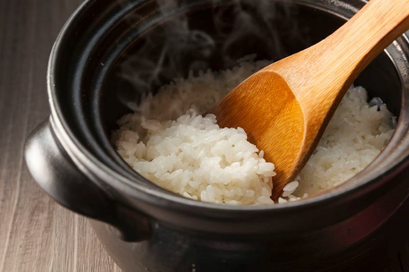黑色鑄鐵鍋用木頭色飯匙盛白色熱騰騰的米飯