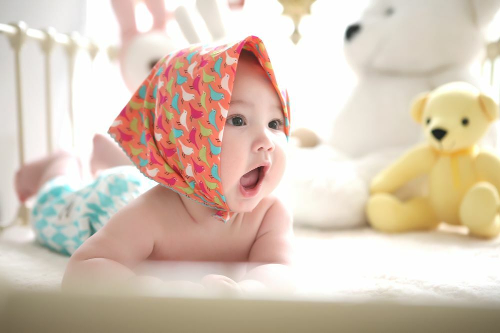 戴著頭巾的寶寶包著尿布趴在床上