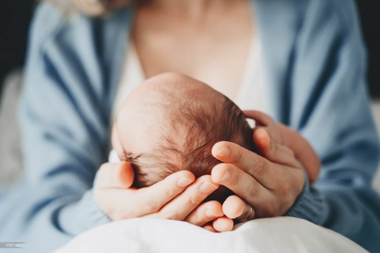 一個媽媽捧著新生兒寶寶在手心