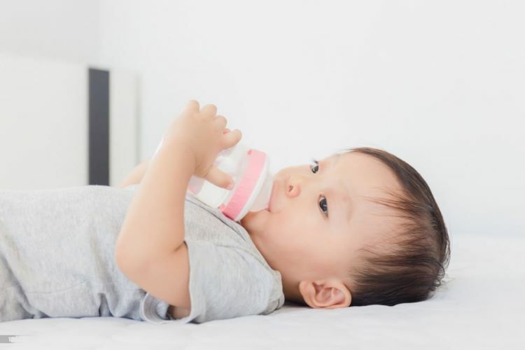 一位寶寶自己捧著奶瓶喝著奶