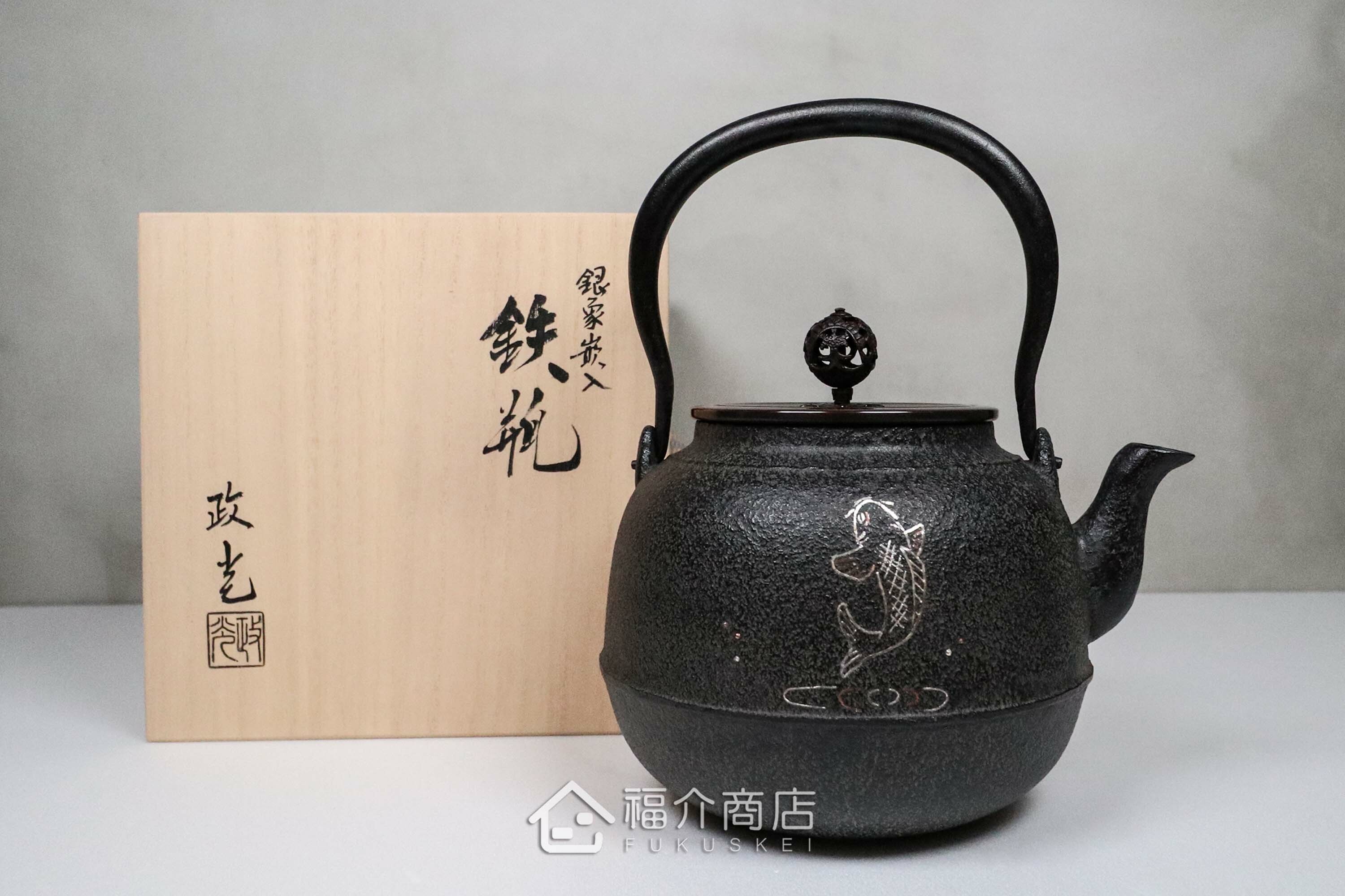 煮水泡茶用的銅蓋鐵壺，壺身象嵌鯉魚紋，木盒包裝