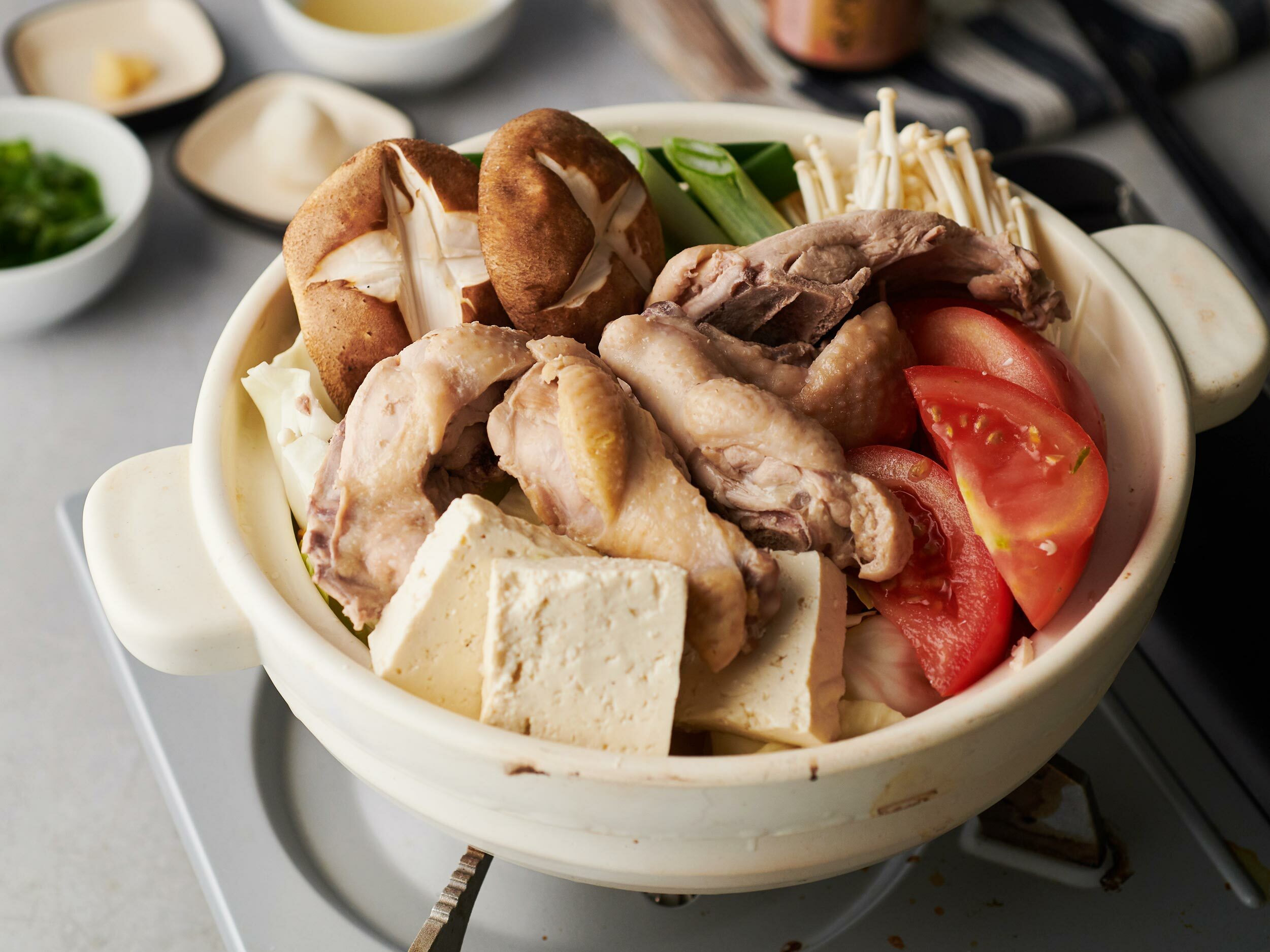 在上桌的鍋內將雞肉、切好的蔬菜、蕈類等鋪陳端整。如果不容易盛裝的話,雞湯先放在別的容器內,之後再注入。