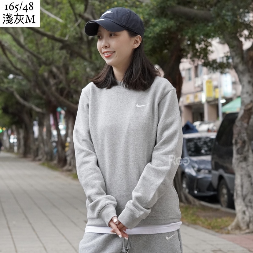 女模穿著Nike Club Fleece 單勾內刷毛大學T淺灰色半身照