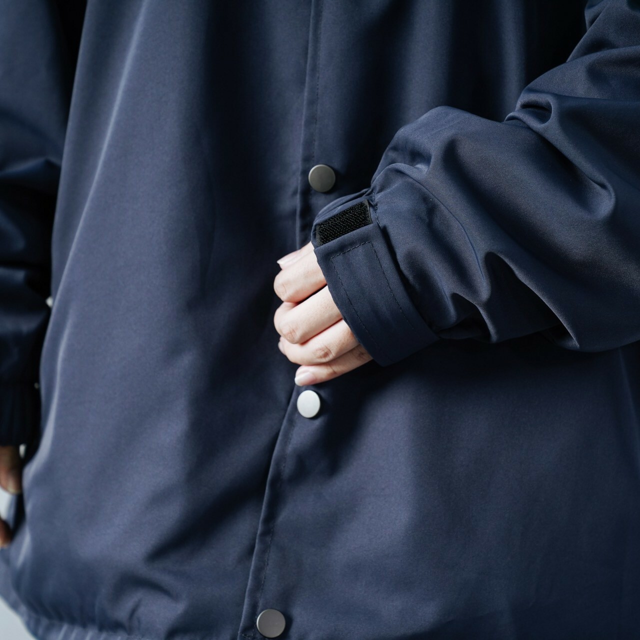 女模穿著#1031 防潑水寬鬆教練外套深藍袖口細節照