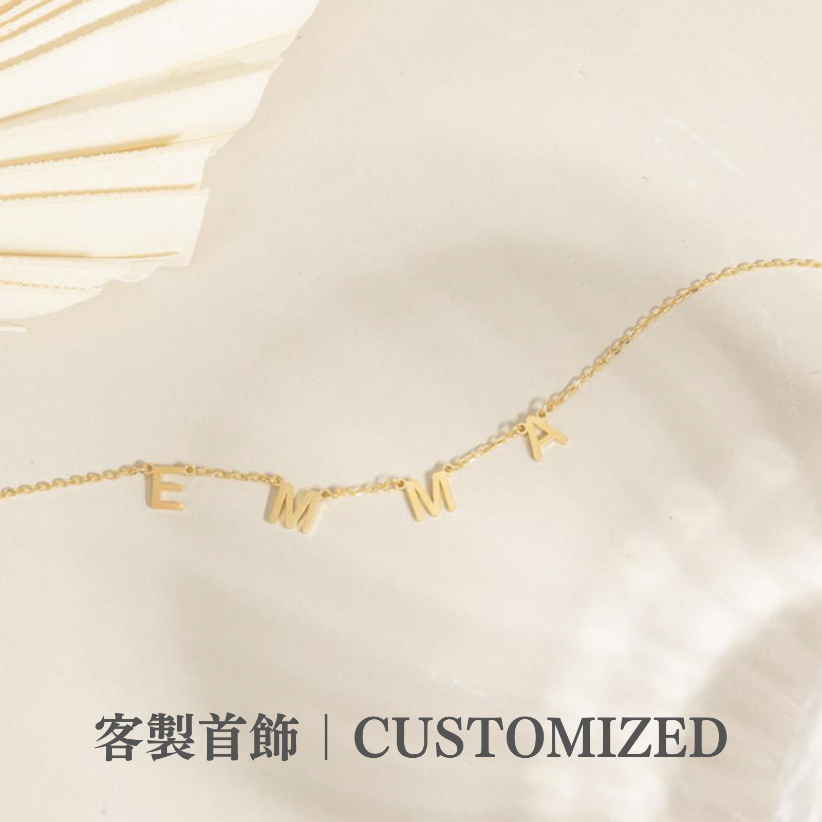 米白色的桌上有一條金色英文字母定製項鍊