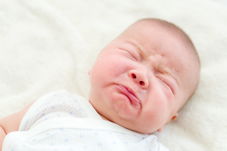 一個剛出生嬰兒在白色的毯子上哭泣。