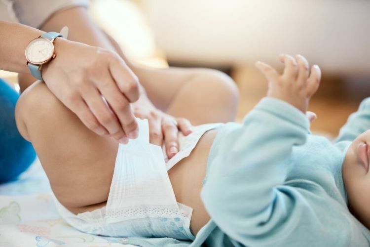 女人替嬰兒換上透氣尿布。