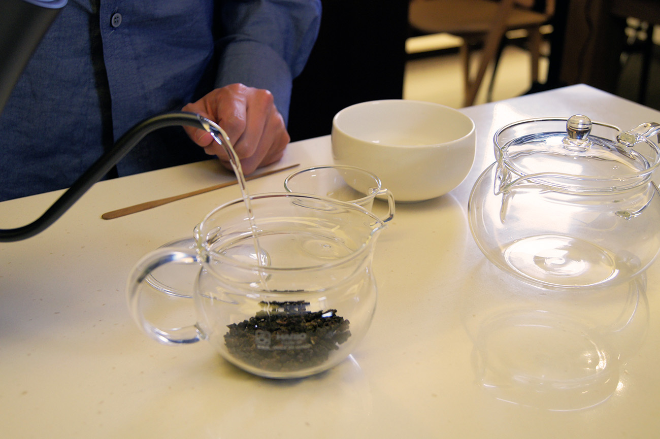 玻璃茶壺裝滿了茶葉正注入熱水