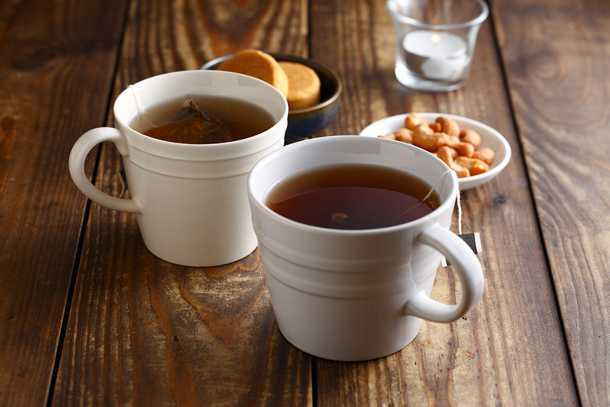 兩杯裝著紅茶茶包的馬克杯搭配茶點