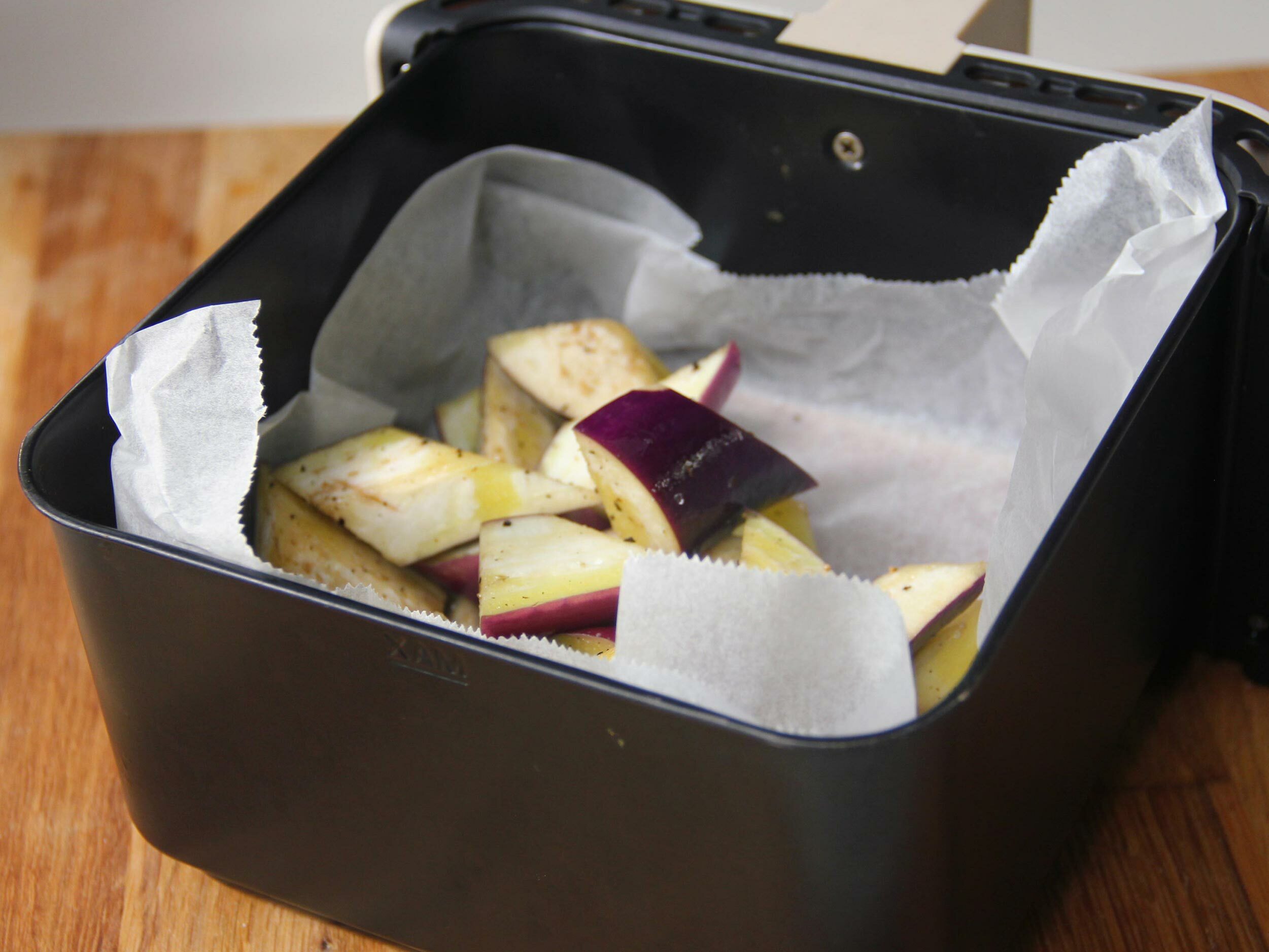 用氣炸鍋將茄子塊、2 湯匙橄欖油和鹽拌一拌,烤 15分鐘