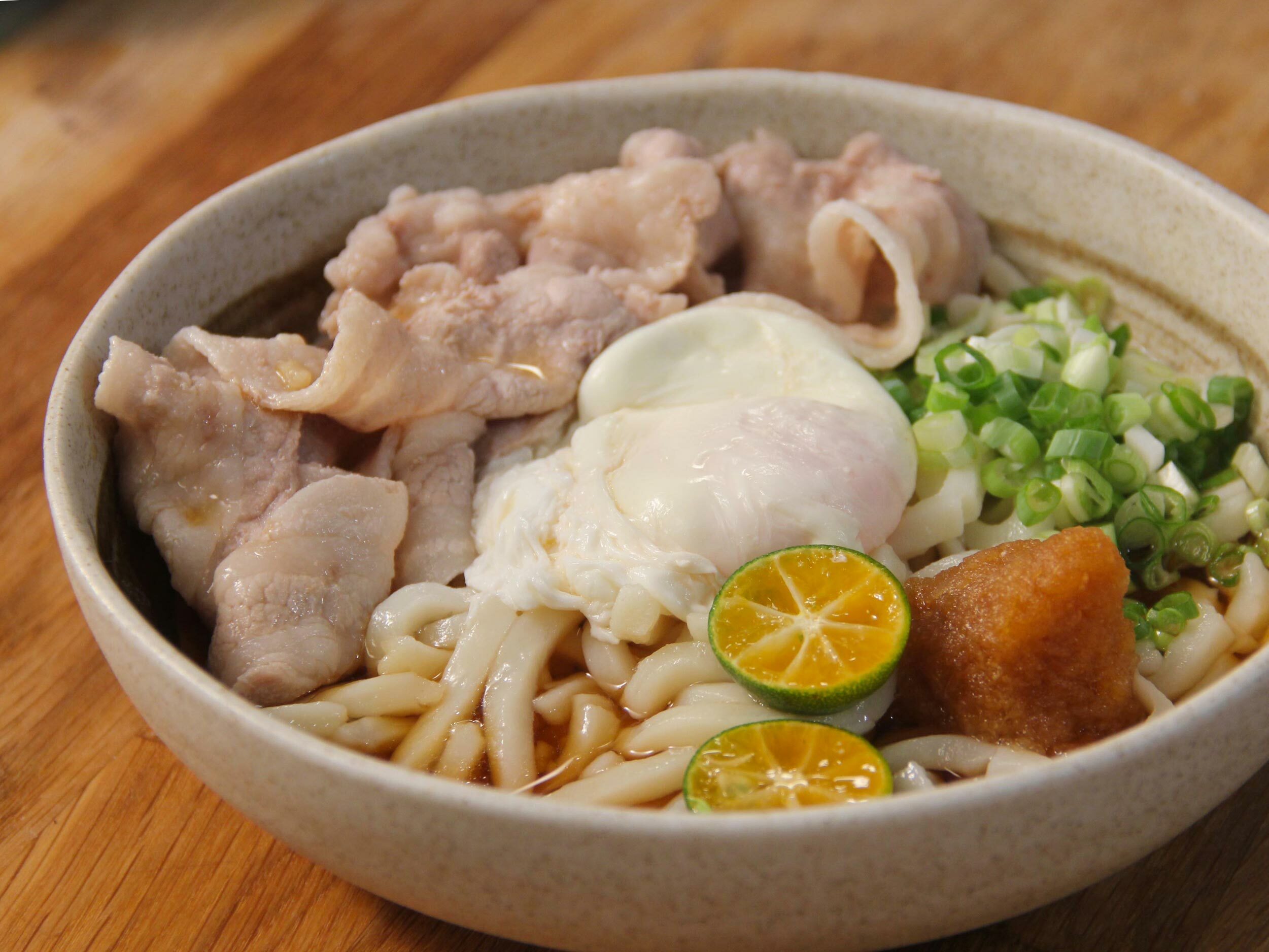 將冷烏龍麵放入碗中，淋上醬汁、放上蘿蔔泥、蔥花、水波蛋與五花薄片，最後加入金吉