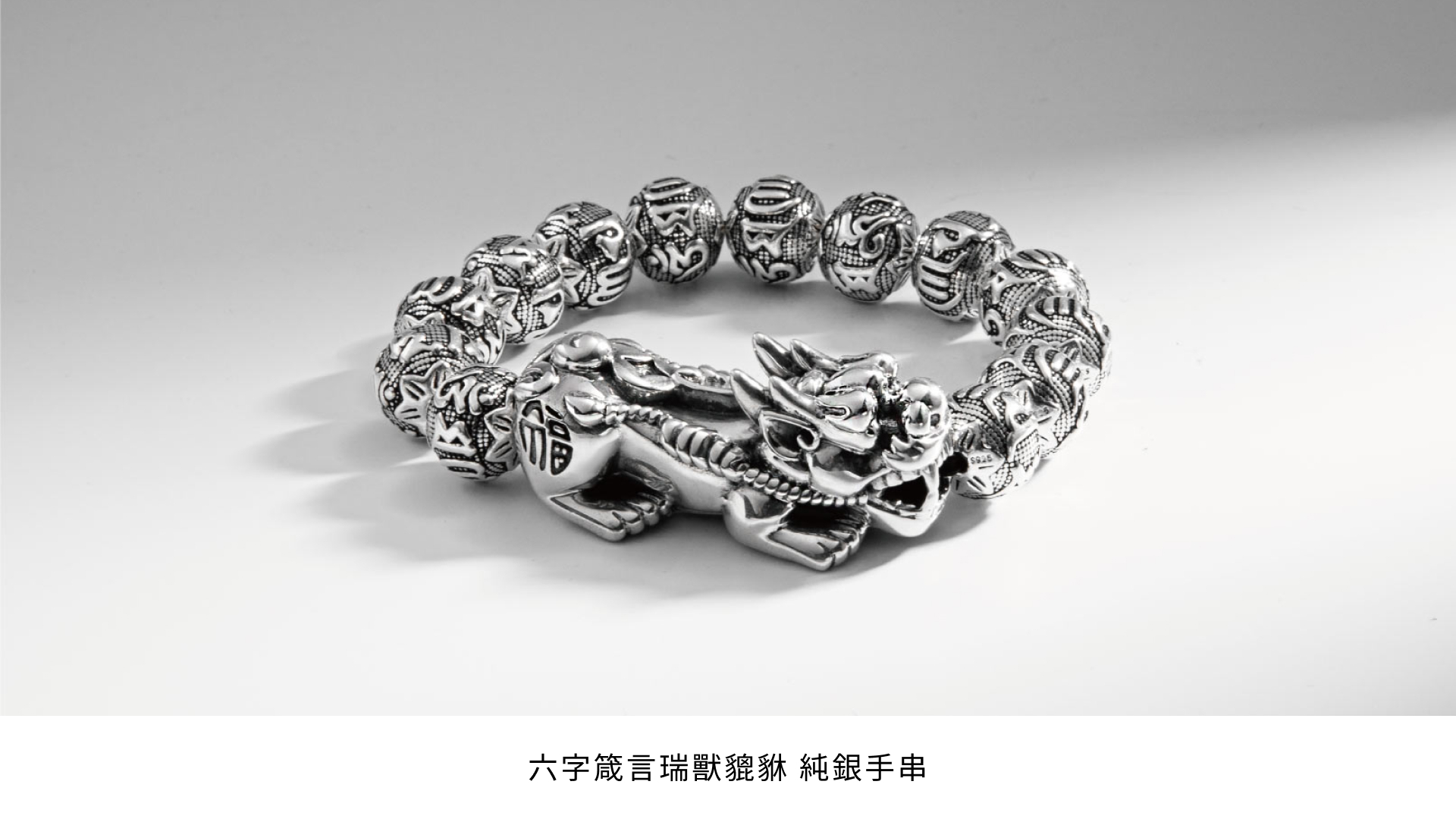 六字箴言瑞獸貔貅純銀手串，精緻的純銀珠子上刻有六字箴言，手串中央是一隻雕刻精美的貔貅，象徵著吉祥和財富。