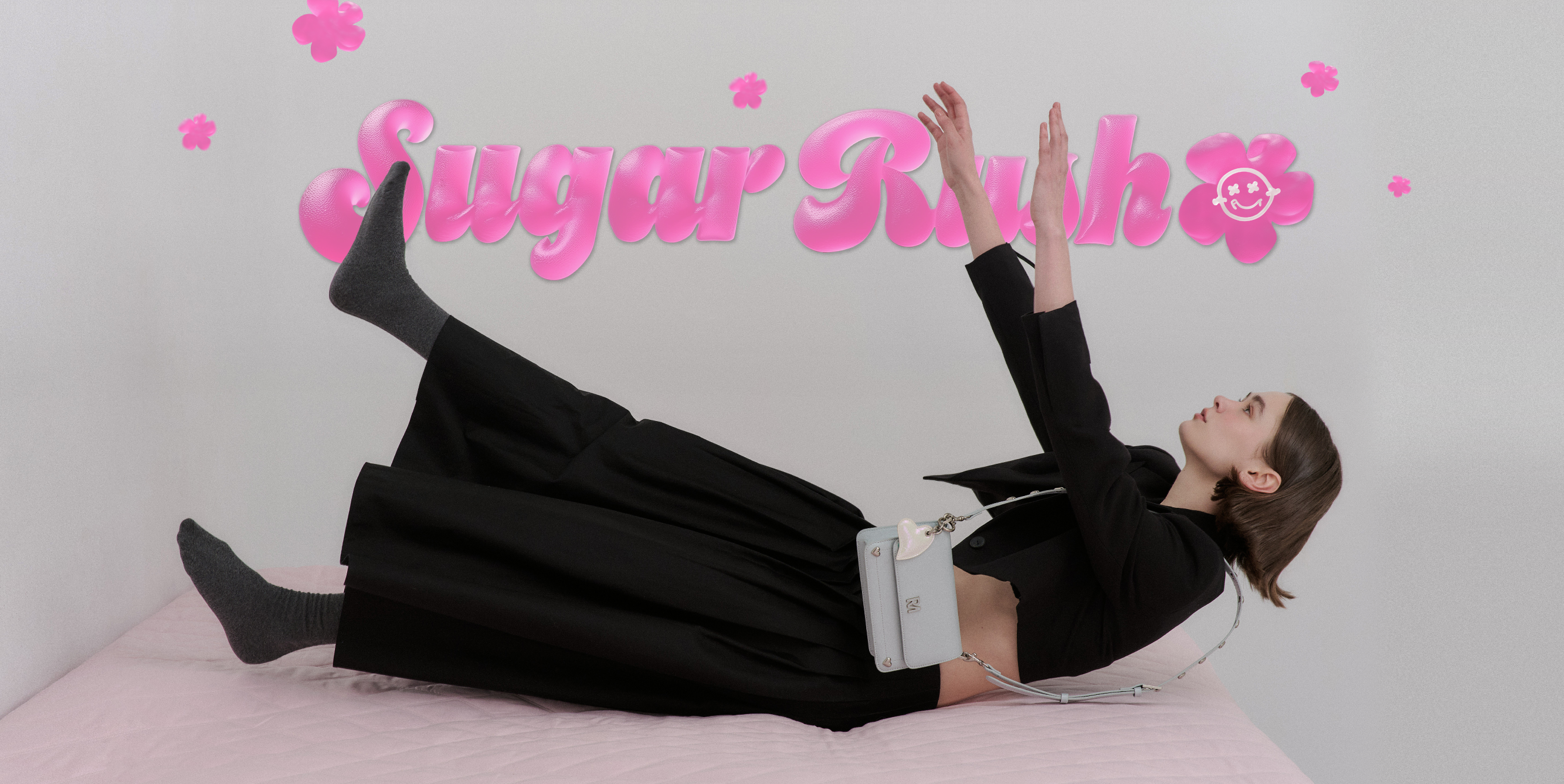 短髮女生穿著黑色洋裝，背著霧藍色Love More 斜背包，躺進菱格紋的粉紅色床墊。