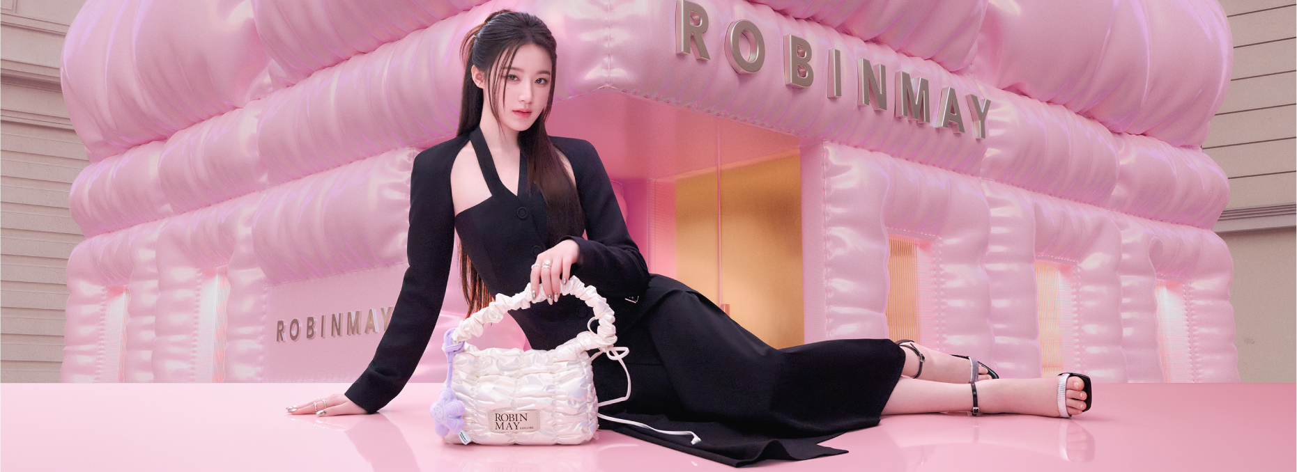 舒華代言系列包款介紹。舒華身穿黑色緊身洋裝，以側臥姿態展示ROBINMAY 舒華系列 白色的Meego 肩背包。