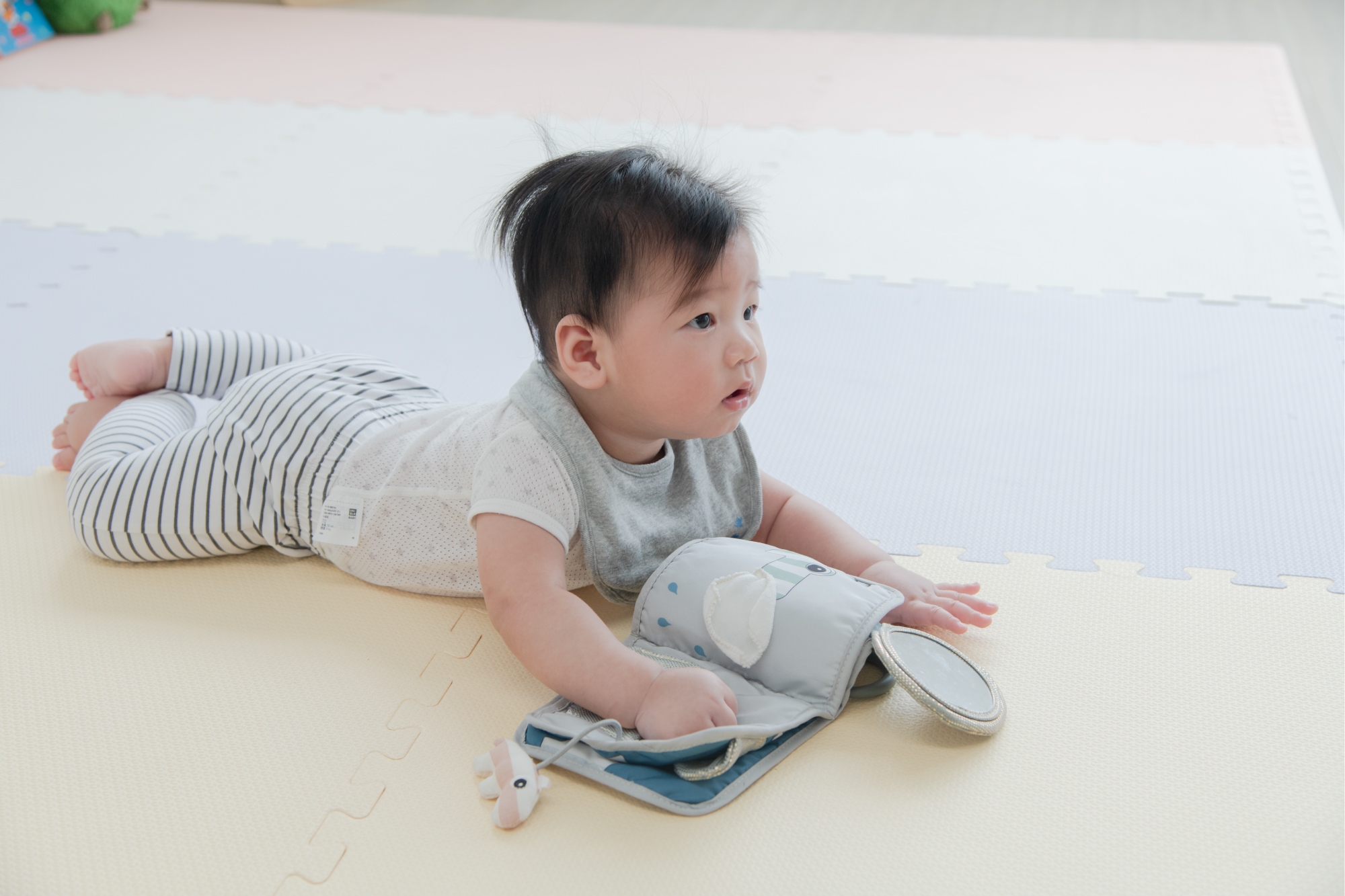 這是一張寶寶在地墊上看布書的照片