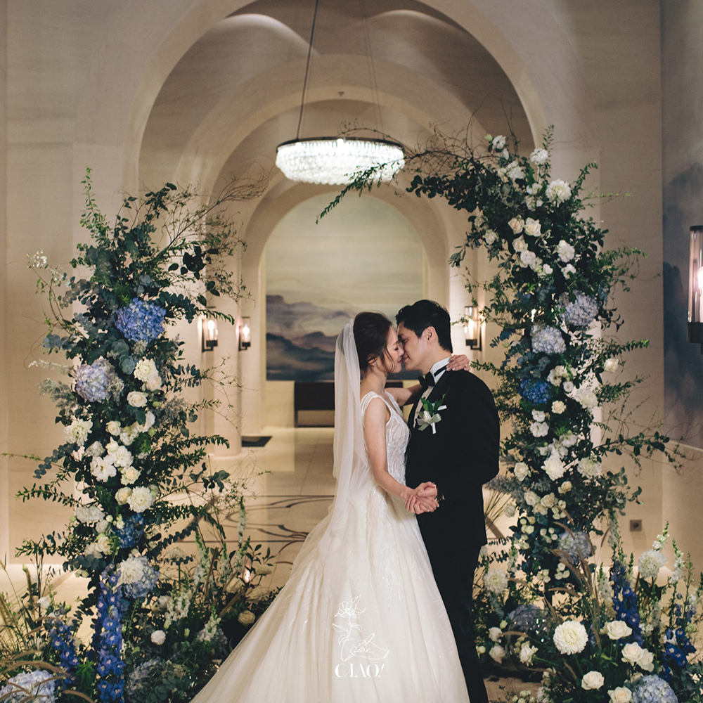 美麗的台北室內婚禮儀式區花藝佈置與新人親吻的照片