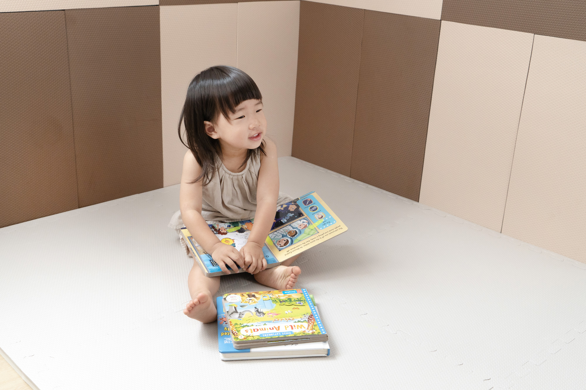 這是一張小朋友在有防撞壁貼的房間裡面看書的照片