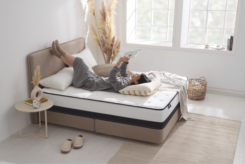 女孩躺在穩穩支撐床墊上,悠哉地看著書。