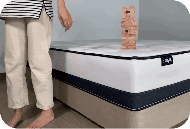 擺放疊疊樂在獨立筒床墊上,一名女孩坐上床邊,疊疊樂完全沒有倒,足見獨立筒能有效抗干擾。