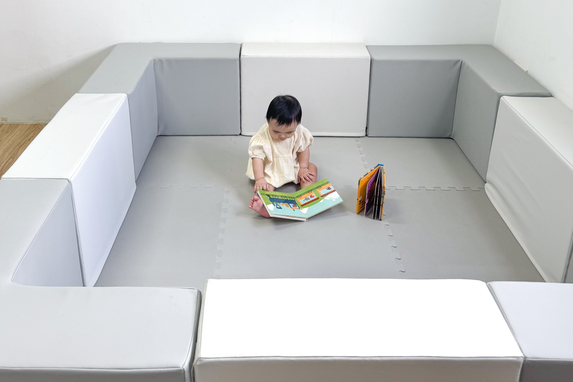 這是一張寶寶在圍欄裡看書的照片