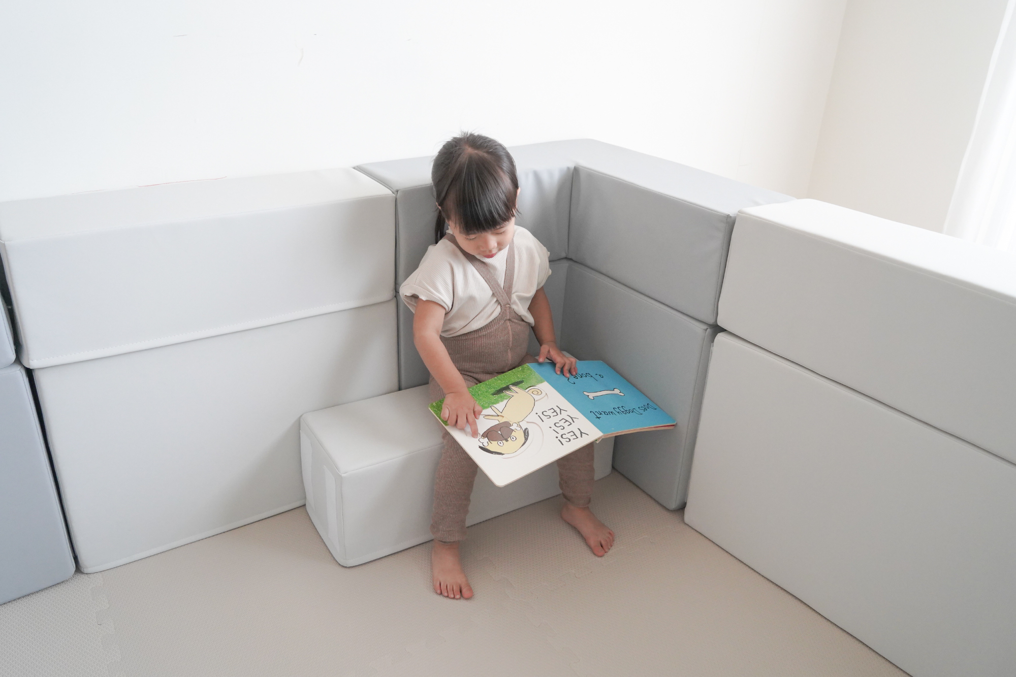 這是一張小孩在圍欄裡看書的照片