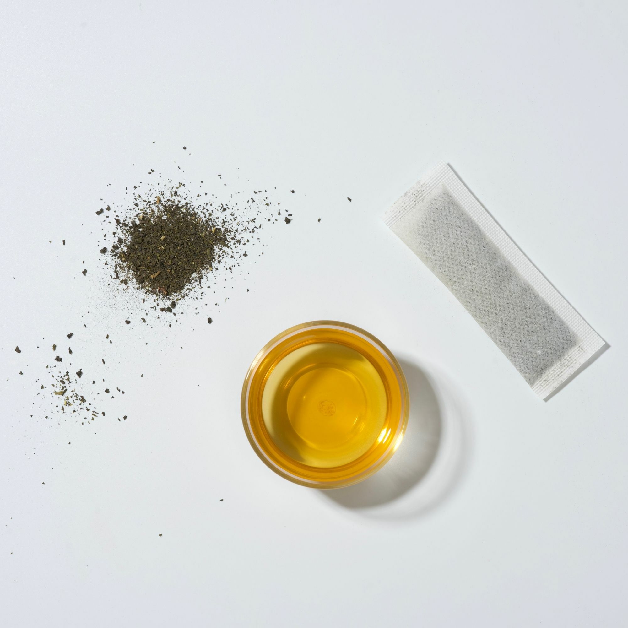 畫面裡，半生熟烏龍茶葉、茶包與橘黃色茶湯