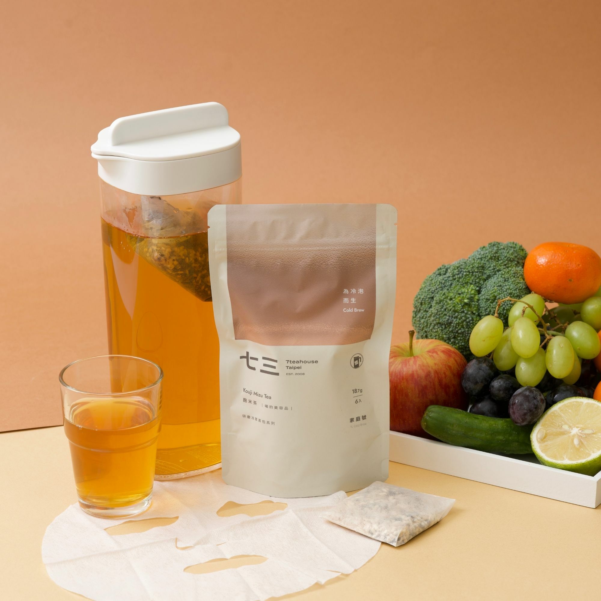 畫面裡，麴米茶 研磨冷萃家庭號大茶包，使用情境應用，可以常溫水沖泡飲用，畫面還有新鮮水果與面膜，呈現喝的美容品的氛圍。