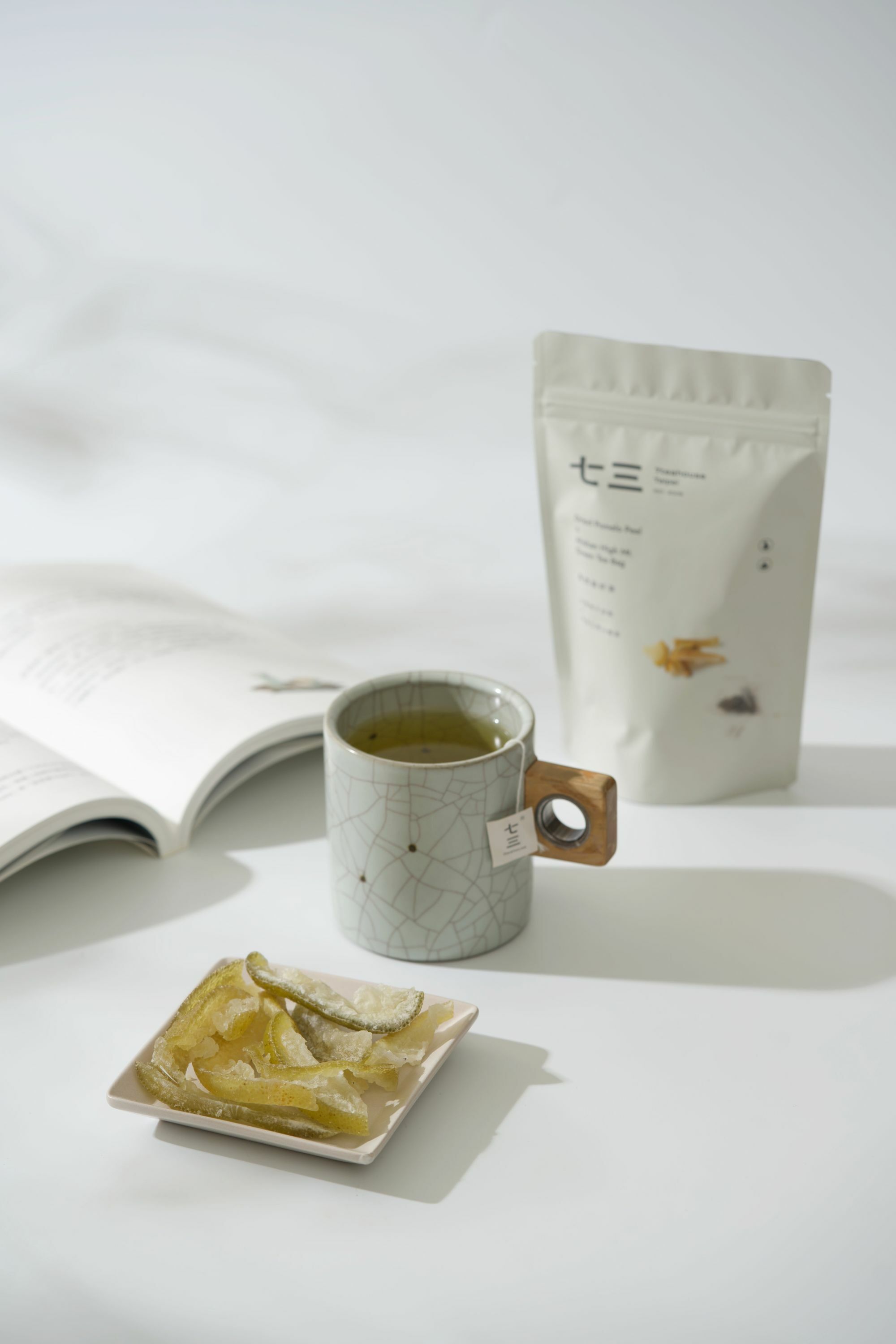 畫面裡,有書本搭配泡著麥香烏龍的馬克杯與芭樂乾和果然是好茶--台南柚子皮乾 & 阿里山高山綠茶商品呈現的午茶時光氛圍。