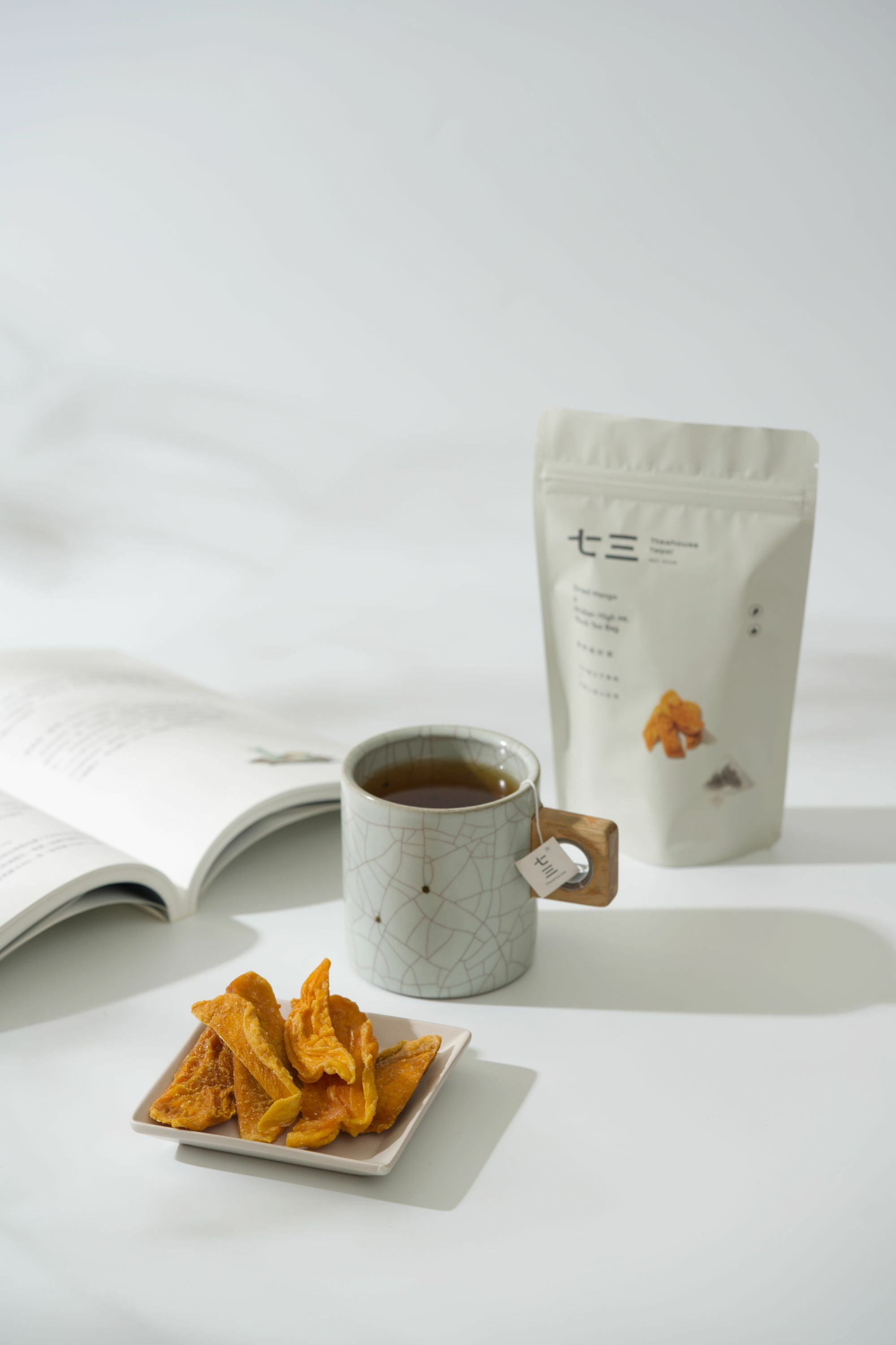 畫面裡,有書本搭配泡著麥香烏龍的馬克杯與芭樂乾和果然是好茶-玉井愛文芒果乾 & 阿里山高山紅茶商品呈現的午茶時光氛圍。