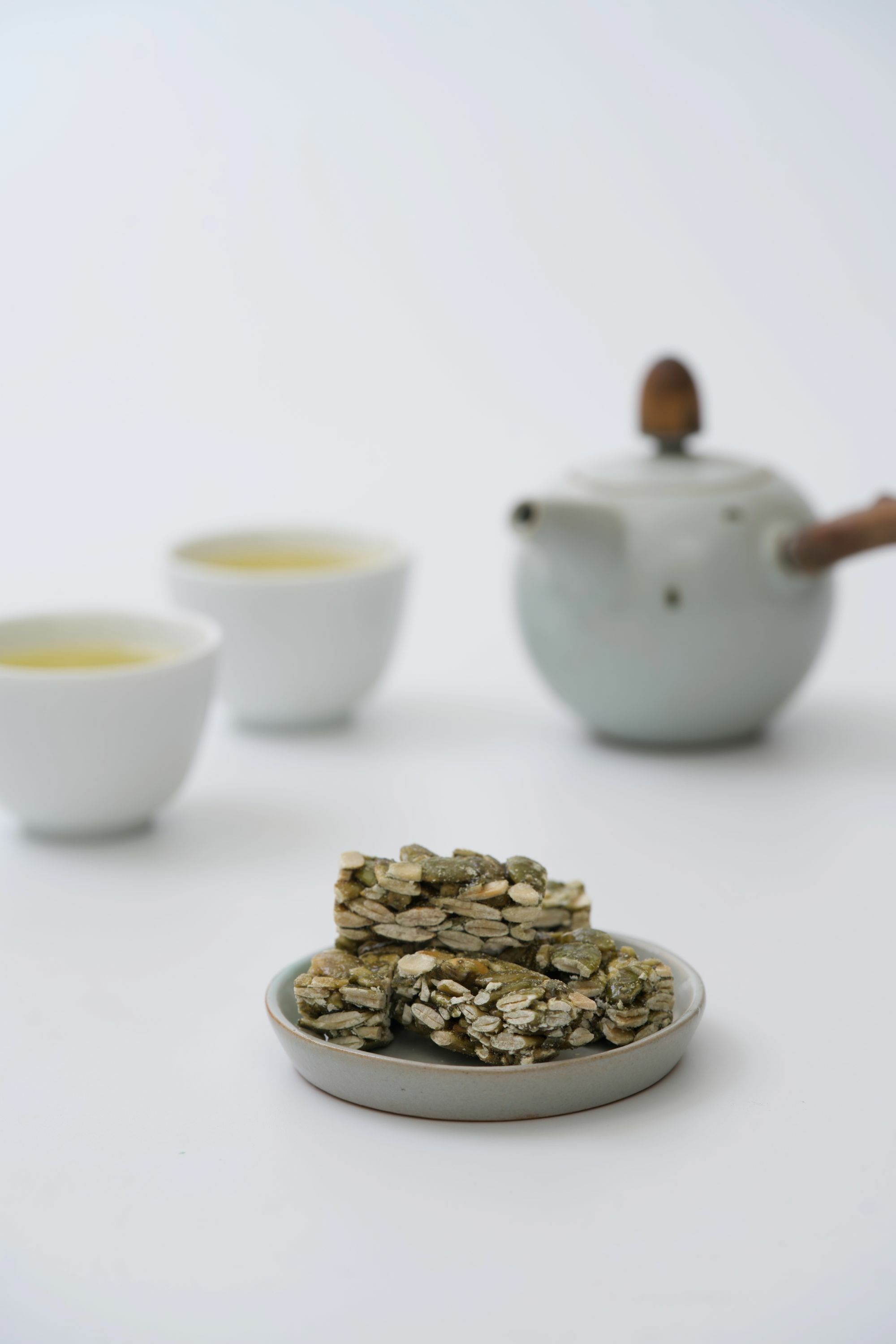 畫面裡,聚焦在清香瓜子酥本身,虛化背景茶杯、茶湯與茶壺。