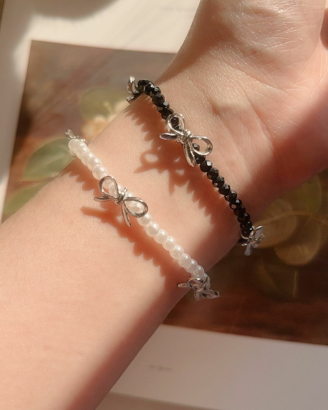 金色、銀色手鍊很多了嗎？ 來個黑色、白色手鍊一起搭配更加分唷🧸  漂亮的串珠手鍊 質地戴起來很有光澤 跟著光線反光亮亮的🫧 三個小蝴蝶結平均分佈 不管在哪個角度，舉手投足都可以看見迷人的蝴蝶結🎀  白色款是貝珠，質感像珍珠 加上最流行都蝴蝶結，非常迷人可愛 而且秋冬好適合珍珠哦🤍  黑色款的珠珠是鑽切版 更多角度可以反射光線 所以看起來總是像水晶黑得發亮🖤✨ 有點酷、也有點辣🤩