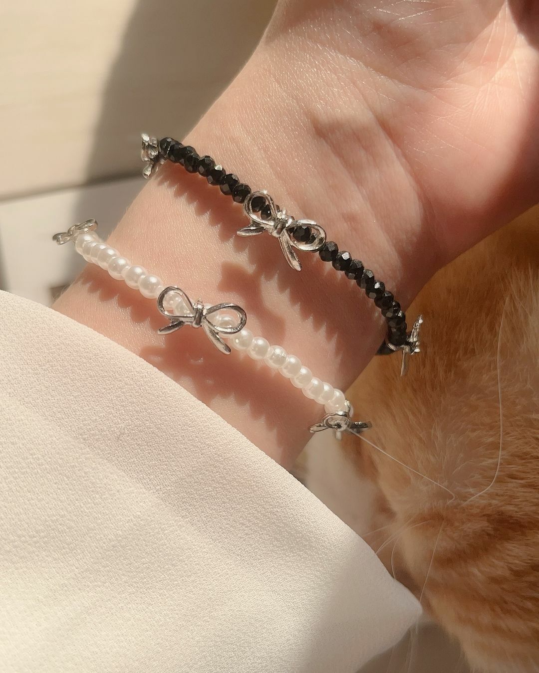 金色、銀色手鍊很多了嗎？ 來個黑色、白色手鍊一起搭配更加分唷🧸  漂亮的串珠手鍊 質地戴起來很有光澤 跟著光線反光亮亮的🫧 三個小蝴蝶結平均分佈 不管在哪個角度，舉手投足都可以看見迷人的蝴蝶結🎀  白色款是貝珠，質感像珍珠 加上最流行都蝴蝶結，非常迷人可愛 而且秋冬好適合珍珠哦🤍  黑色款的珠珠是鑽切版 更多角度可以反射光線 所以看起來總是像水晶黑得發亮🖤✨ 有點酷、也有點辣🤩