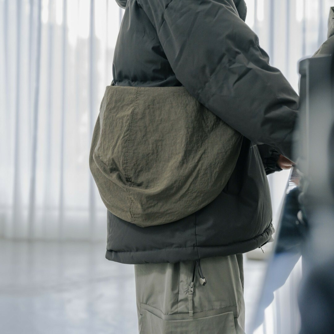 男模背著半月型日系斜挎包灰綠色側面照