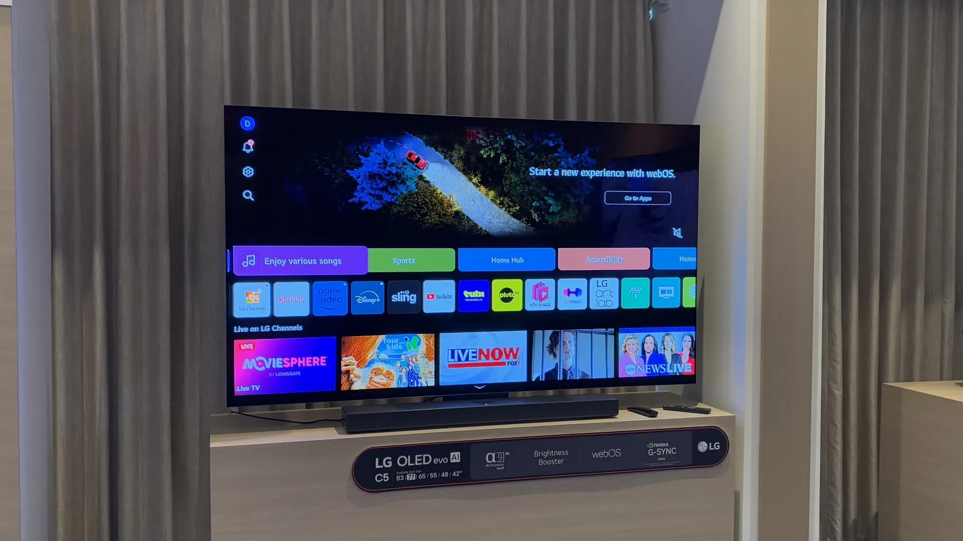 LG C5 OLED 智能電視展示，屏幕顯示基於webOS的用戶界面，包括多個流媒體應用程式（如Netflix、Prime Video、Disney+等）和即時電視選項，電視下方標示其特性如OLED evo AI、亮度增強器、NVIDIA G-SYNC支援等。