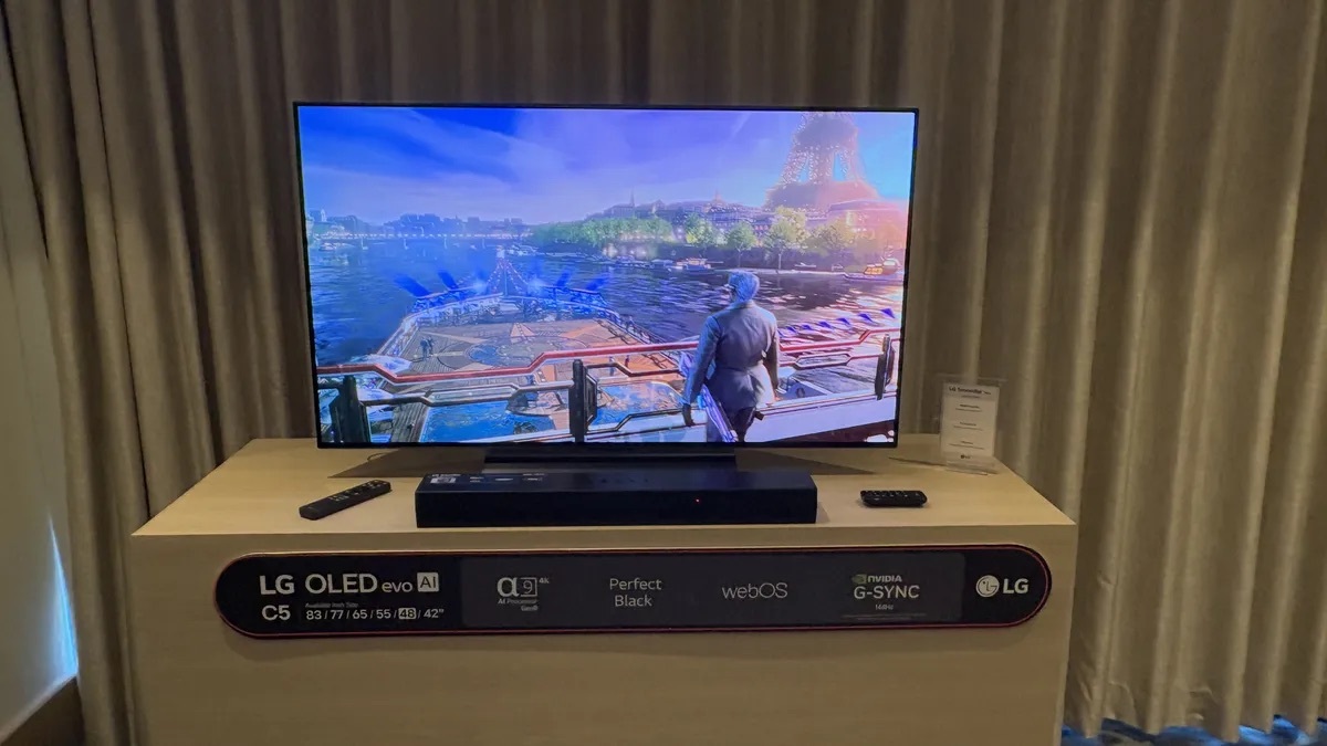 LG C5 OLED 智能電視展示中，屏幕顯示高畫質遊戲場景，背景為巴黎的標誌性建築埃菲爾鐵塔。電視放置於展示台上，展示台標示了電視的主要功能特性，包括OLED evo AI、Perfect Black、webOS 和 NVIDIA G-SYNC 支援等，適合高性能遊戲和觀影體驗。