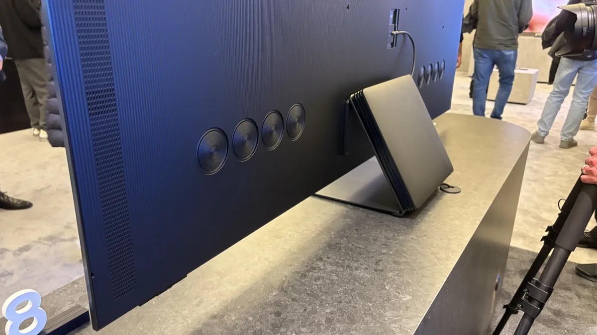 Samsung S95F OLED 智能電視背部細節展示，顯示內建揚聲器和通風設計。旁邊擺放著連接模塊，突顯其模組化設計和靈活的連接選項，專為提升音頻及視覺體驗設計。