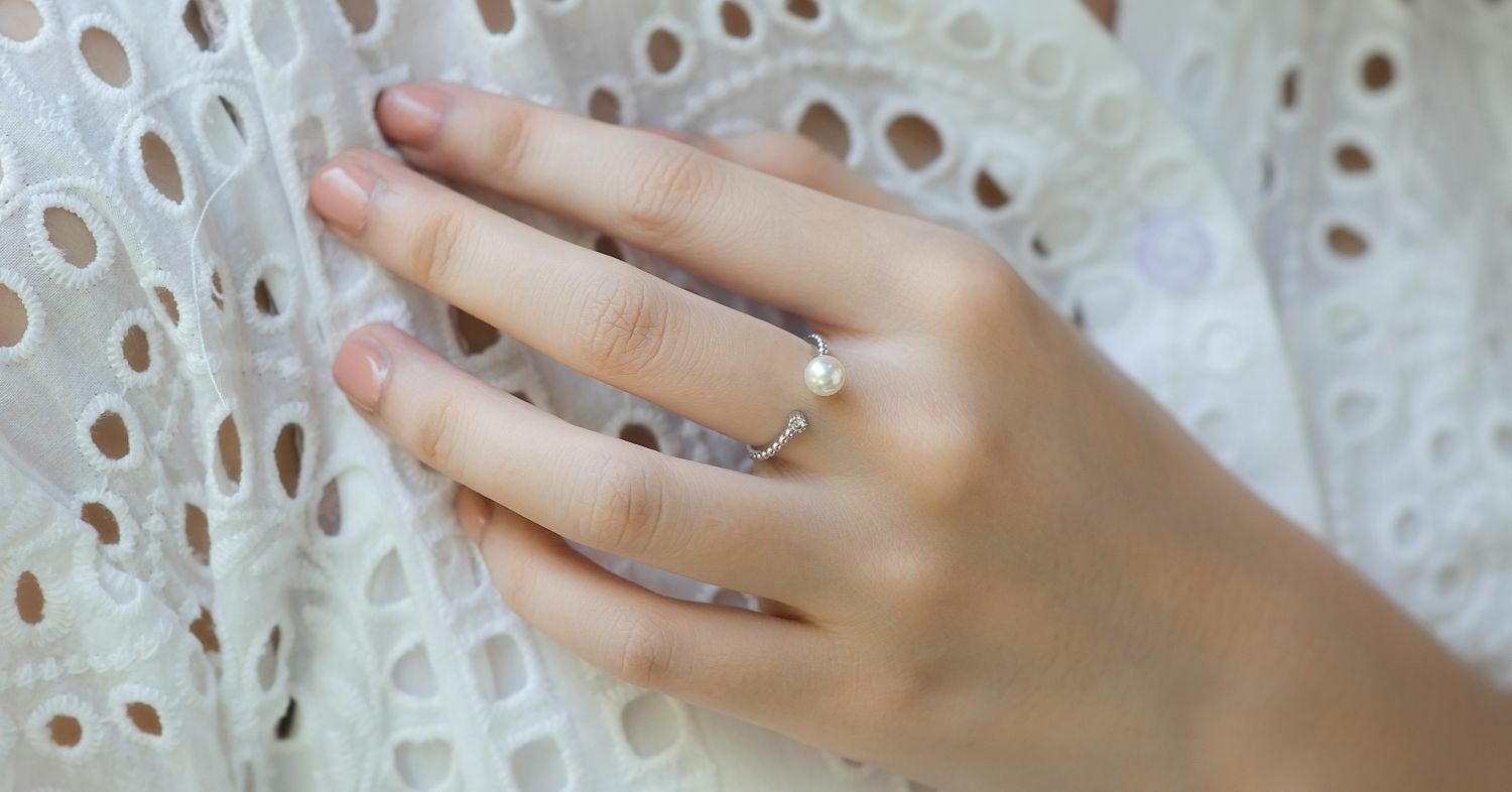 Elegant 18K gold ring with a delicate akoya pearl, worn on a woman's hand.